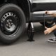 Driver changing a car tire with a jack and wrench, illustrating step-by-step tire replacement