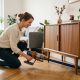 Dyson cordless vacuum standing on a polished dark hardwood floor in a sunny modern living room.