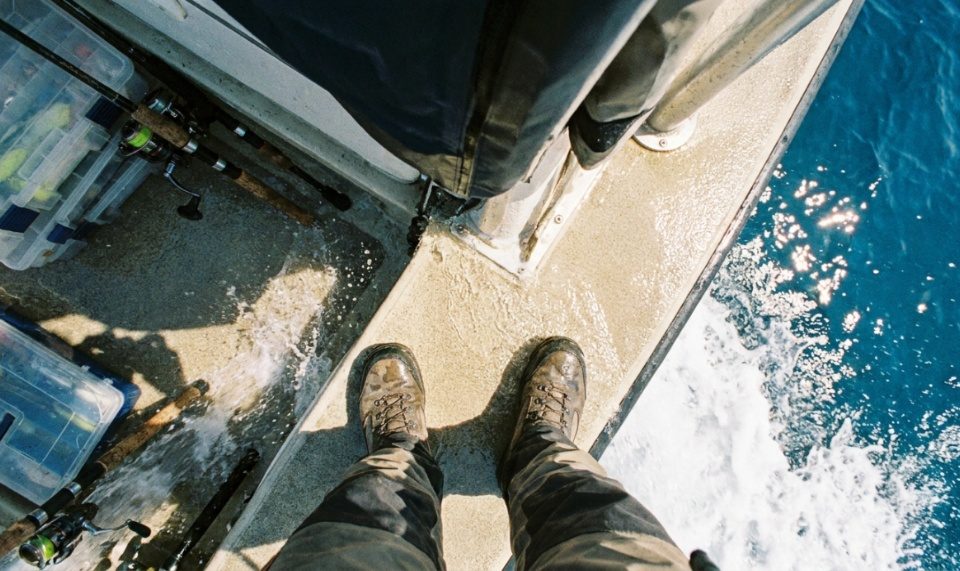 An angler wearing high-traction fishing shoes on wet river rocks.