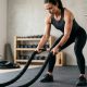 A fit person gripping a heavy battle rope in a home gym.
